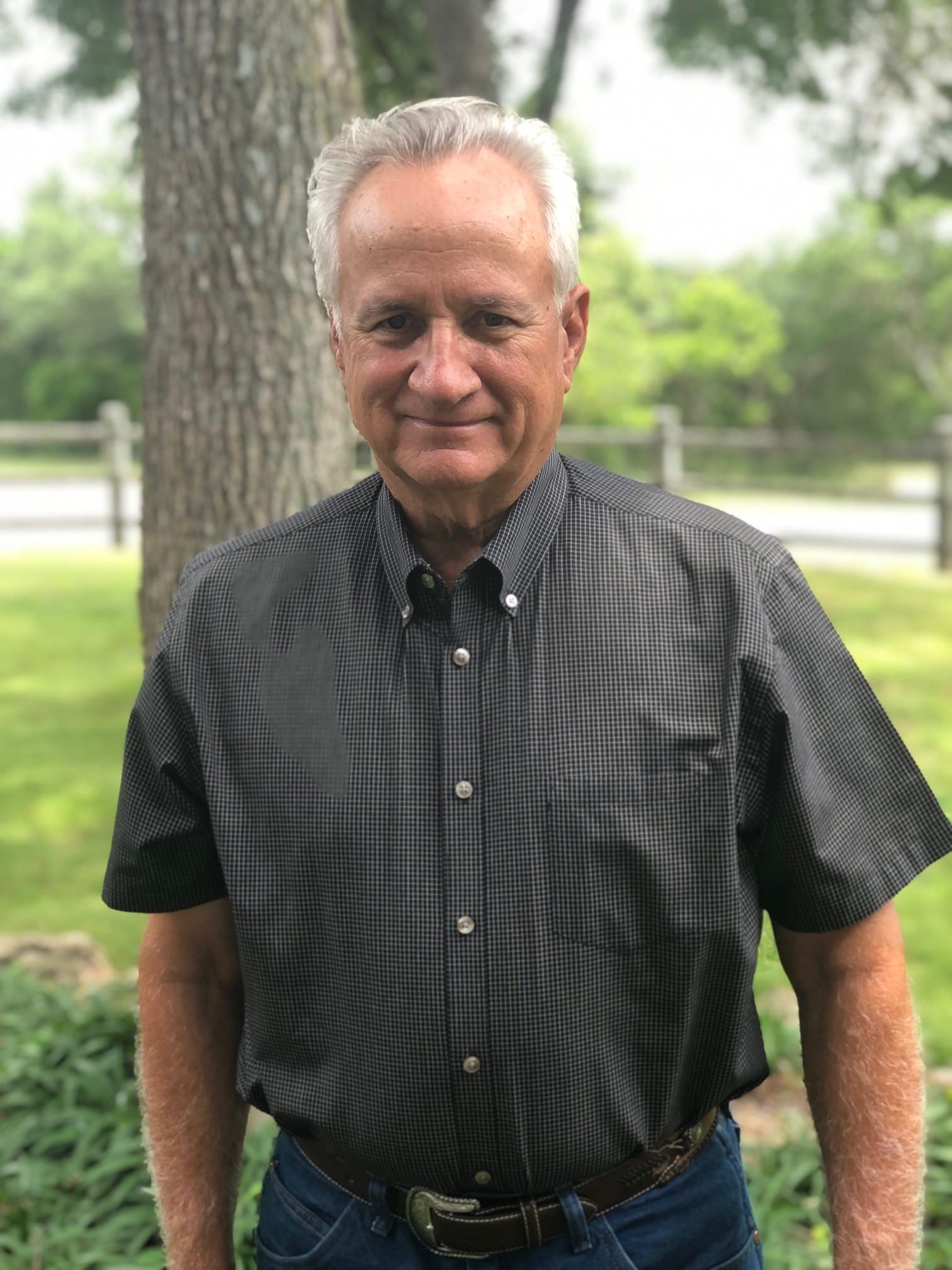 A man in black shirt standing next to tree.