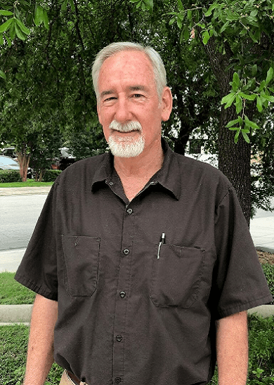 A man with white hair and beard wearing a black shirt.