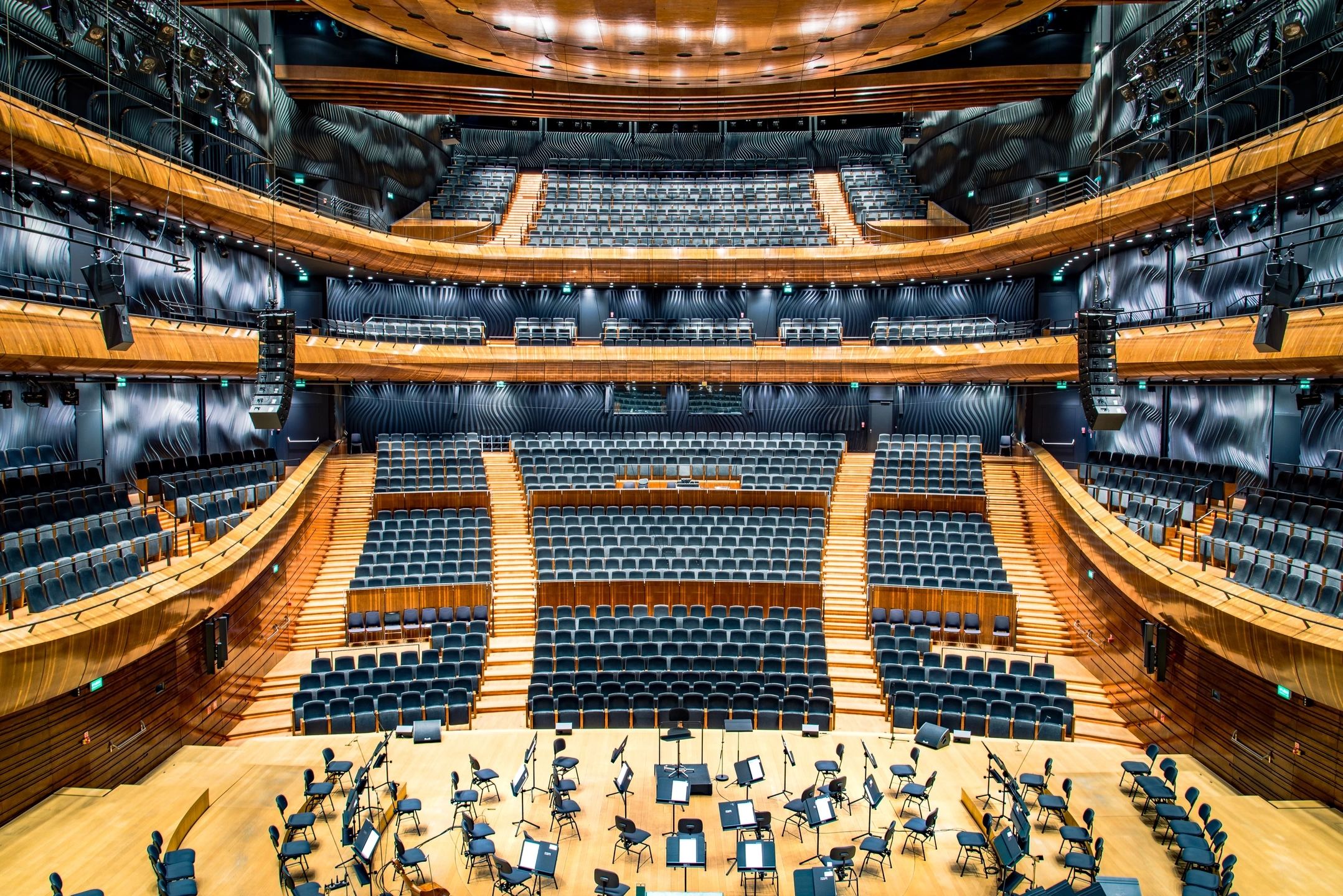 A large auditorium with many chairs and people playing music.