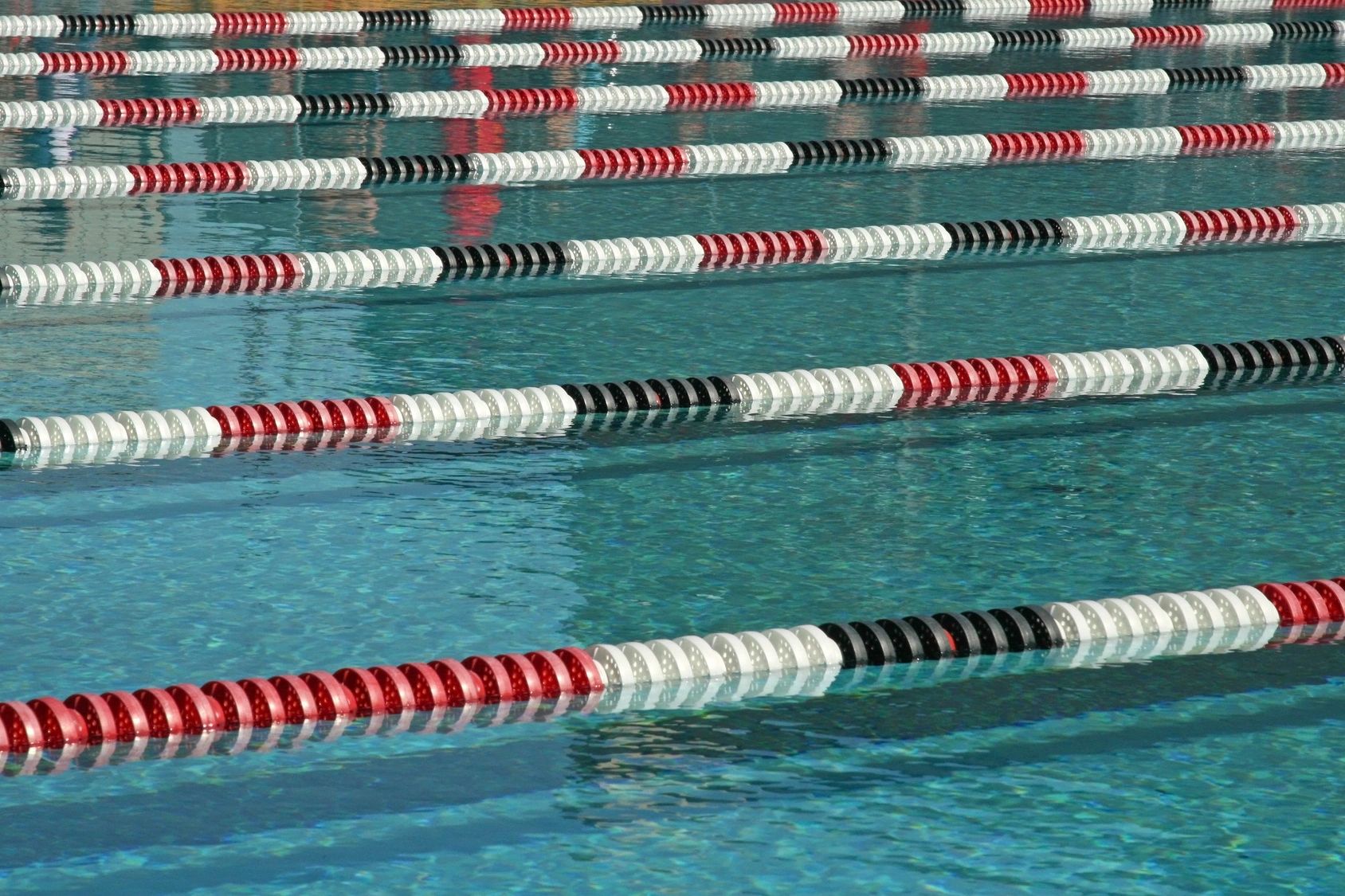 A swimming pool with many lanes and black, white and red stripes.