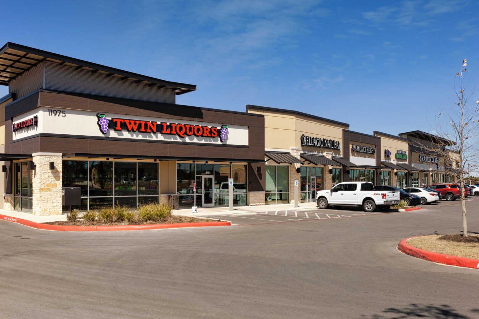 A parking lot with several stores and cars parked on the side.